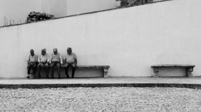 grayscale photo of four men sitting on bench along the 1153517
